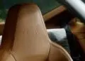 نمای نزدیک از یک صندلی خودرو با چرم قهوهای روشن که طرح برجسته یک اُسلات (گربه ببری) روی پشتسری و الگوی پارچهای شطرنجی روی پشتی آن دیده میشود؛ طرحی الهامگرفته از سبک سفارشی پورشه 911 GT3 زوندروونش.