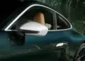 نمای نزدیک از کنار یک خودروی اسپرت 911 GT3 زوندروونش به رنگ سبز تیره با آینه بغل سفید، صندلی چرمی قهوهای روشن و پسزمینهای از جنگل.