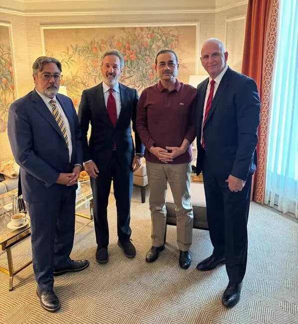 چهار مرد که در یک دفتر کنار هم ایستادهاند و به سمت دوربین نگاه میکنند