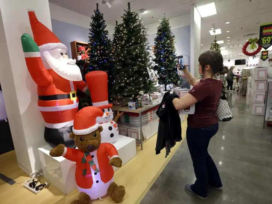 زنی در فروشگاه J.C. Penney در سیتل، جمعهٔ ۲۴ نوامبر ۲۰۱۷، در حال عکاسی از درختهای کریسمس مصنوعی است. جمعهٔ سیاه دیگر بهجای یک روز خاص که مردم زود بیدار میشدند تا کالاهای تخفیفی را بهدست آورند، تبدیل به یک فصل کامل تخفیف شده است؛ بنابراین خریداران ممکن است نیازی به حضور در فروشگاهها احساس نکنند. (عکس AP/الین تامپسون)