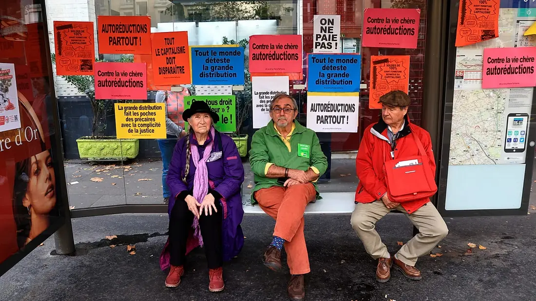 افراد در یک پناهگاه نشستهاند و در کنار دیگران برای راهپیمایی اعتراضی علیه هزینهٔ بالای زندگی و بیتوجهی به تغییرات اقلیمی در پاریس جمع میشوند