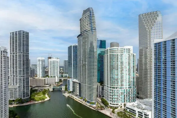 نمایی از افق میامی که یک قایق در آب و برجهای مسکونی براق را نشان میدهد.