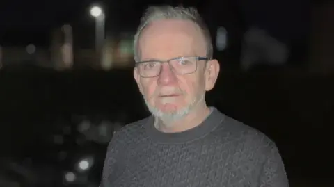 سیاران اودوهرتی از BBC یک پلیور به سبک آرون بر تن دارد. او در یک ایستگاه شارژ خودروهای الکتریکی ایستاده است؛ شب است و محیط بسیار تاریک است.