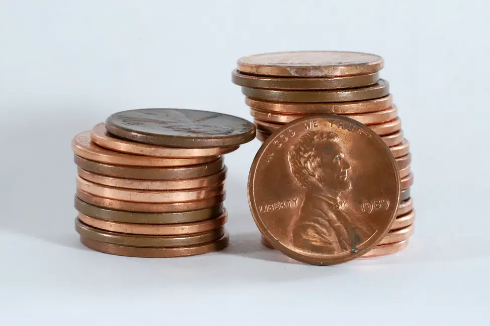 تصویر جزئیاتی از یک دسته سکه پنی ایالات متحده (یک سنت) بر پسزمینهٔ سفید.