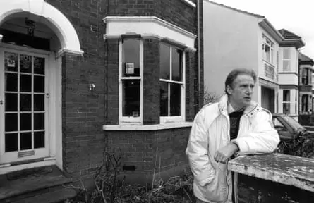 عکس سیاهوسفید پل براون که در مقابل یک خانه ایستاده است