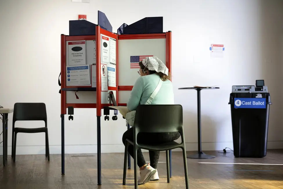 یک رأیدهنده در حال انداختن رأی خود به صندوق در یک حوزه انتخاباتی در آرلینگتون، ویرجینیا.