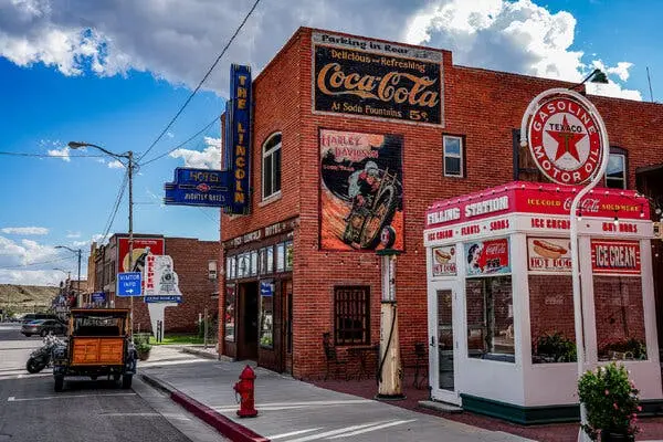 یک ساختمان دو طبقه از آجر قرمز در کنار یک مغازه کوچک سفید با سقف قرمز قرار دارد که روی آن نوشته شده «FILLING STATION». روی ساختمان آجری تابلویی با نوشته «THE LINCOLN» نصب شده و در کنار آن تبلیغات نقاشی‌شده قدیمی کوکاکولا و هارلی-دیویدسون دیده می‌شود، در حالی که روی مغازه سفید تابلوهایی برای تبلیغ هات‌داگ و بستنی وجود دارد.