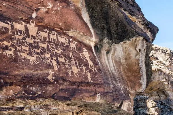 سنگ‌نگاره‌هایی که حیوانات و انسان‌ها را به تصویر می‌کشند، روی دیواره یک صخره دیده می‌شوند.