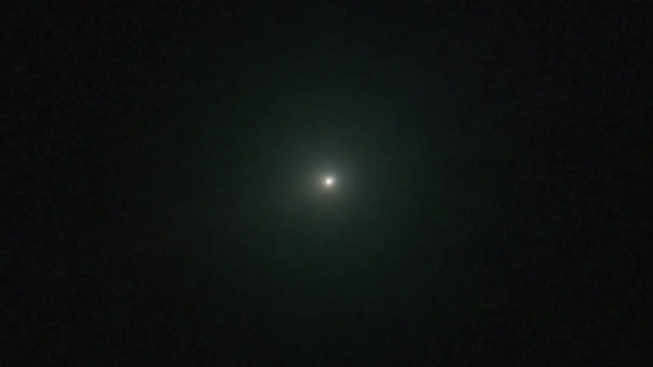 تصویری از دنباله‌دار 3I/ATLAS که به صورت نقیطه‌ای سفید با ته‌رنگ سبز ظاهر شده است.