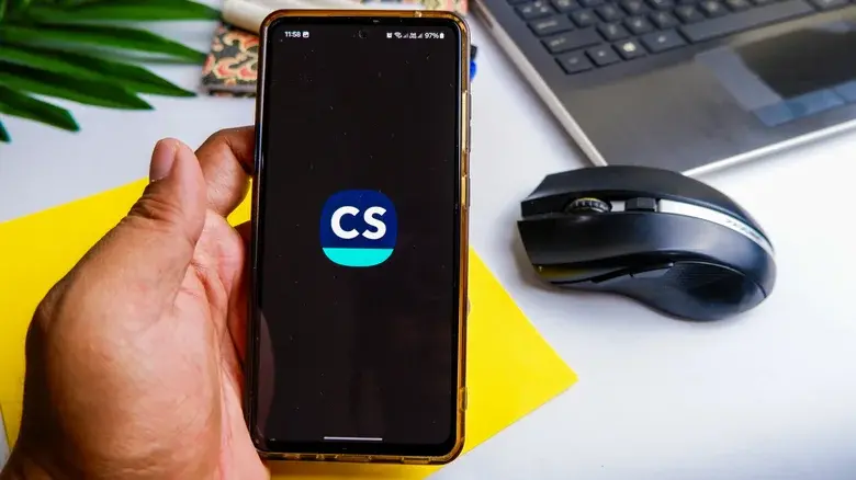 مردی که گوشی را در دست گرفته و لوگوی CamScanner روی صفحه آن نمایش داده شده است