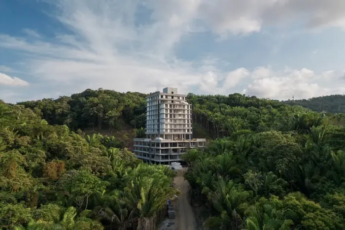 یک برج نیمهتمام با جنگل سرسبز در کنارش قرار گرفته