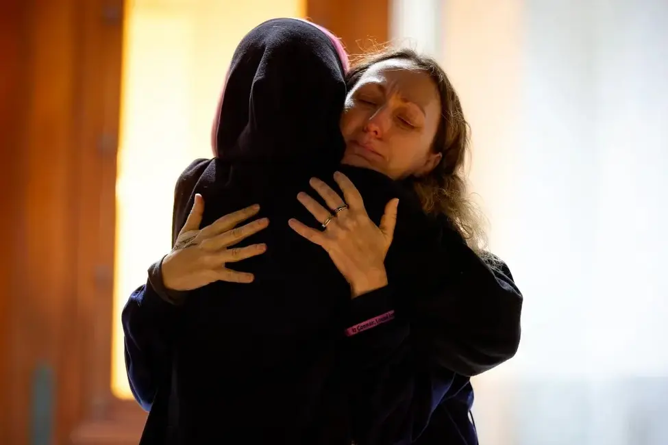 نمای نزدیک دو نفری که در حال در آغوش گرفتن یکدیگر هستند؛ یکی از آنان سعی می‌کند.