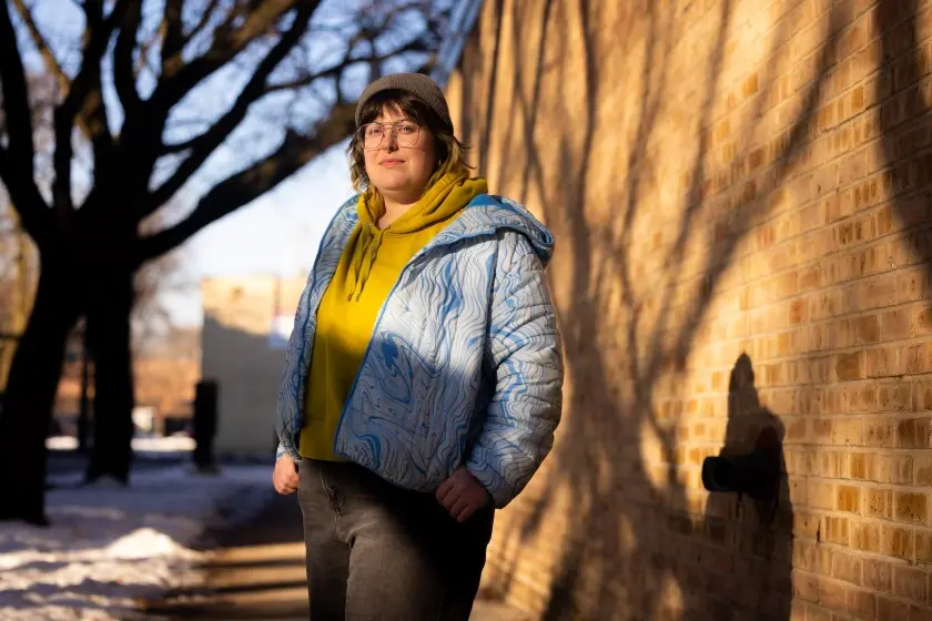 امیلی بین در خارج از آپارتمان‌یش در ایج‌واتر، سمت شمالی، می‌گوید پوشش افزایشی ۱۰۰ دلاری ماهانه حق بیمهٔ سلامت‌اش دشوار است. 