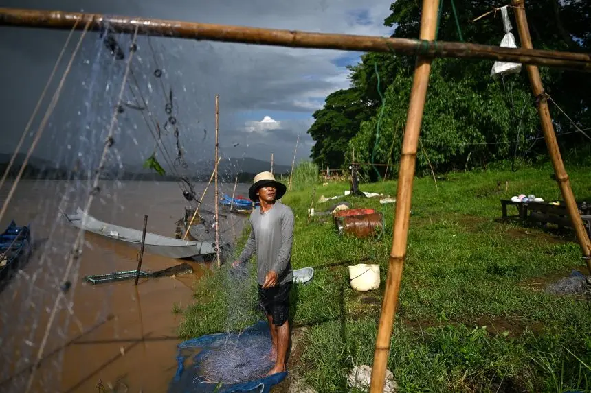 ماهیگیر تایلندی سوات کائودام در حال مرتبسازی تور ماهیگیریاش در امتداد سواحل رودخانهٔ مکونگ، در منطقهٔ مثلث طلایی، استان چیانگرای، شمال تایلند.