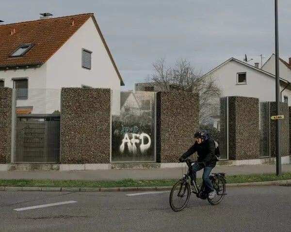 دوچرخه‌سواری که از کنار حروف «A.F.D.» که بر یک دیوار اسپری شده عبور می‌کند.