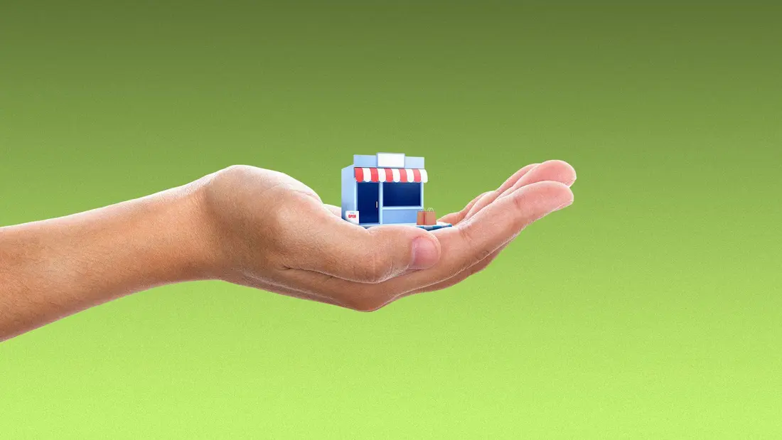 تصویر دست در حال نگه داشتن یک فروشگاه کوچک